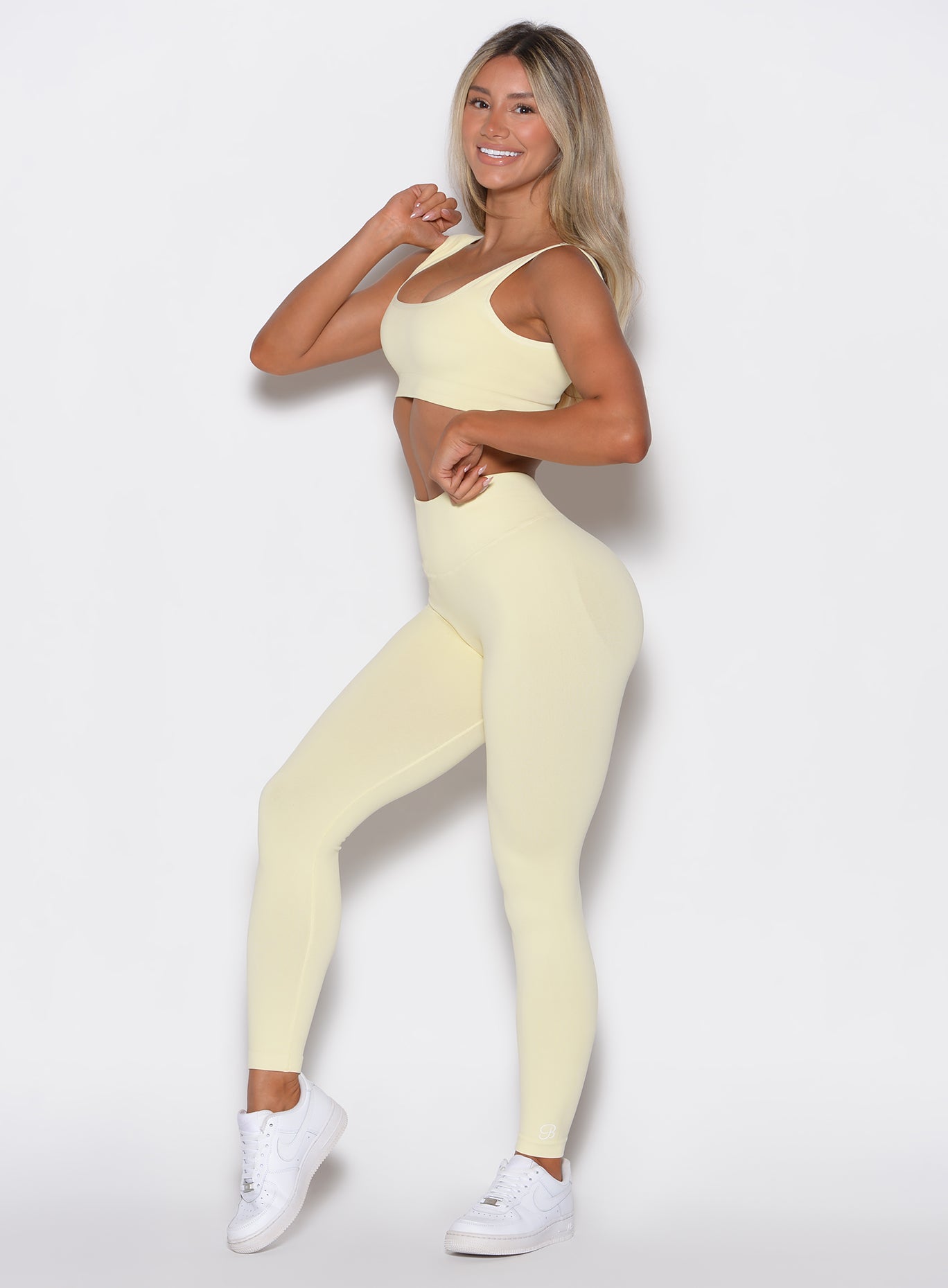 Left-side profile view of a model wearing our V Seamless leggings in Mellow Yellow, complemented with the matching top