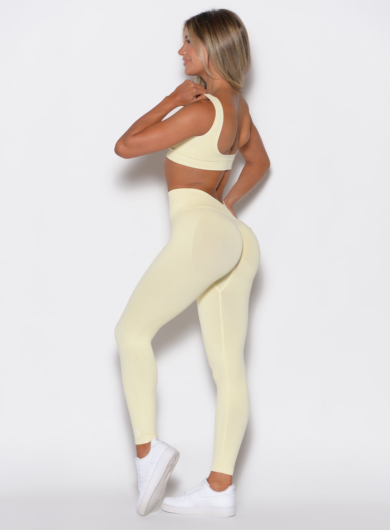 left side profile view of a model wearing our V Seamless leggings in Mellow Yellow, complemented with the matching bra