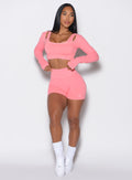 front profile view of a model wearing our v seamless shorts in flamingo color along with the matching pullover 