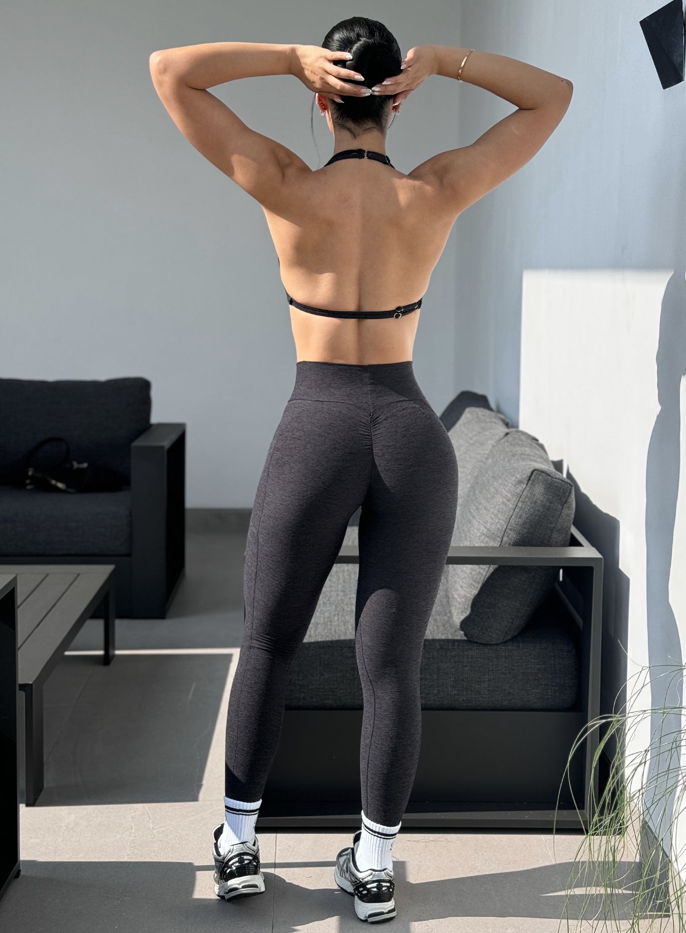 Back profile view of our model in outdoors wearing the Curves 2.0 Leggings in Onyx color paired with the matching top