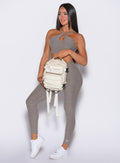 front profile view of our model holding a backpack wearing the Bombshell Bunny Leggings in smoked taupe color