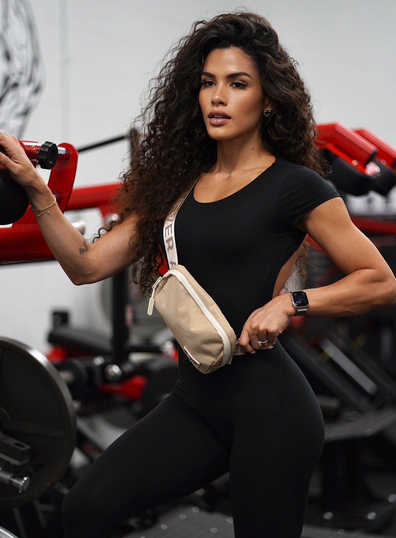 gym shot of model wearing a black bodysuit and the WOLFpak cross over bag