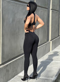 Left side picture of a model facing a wall wearing our black zip bodysuit 