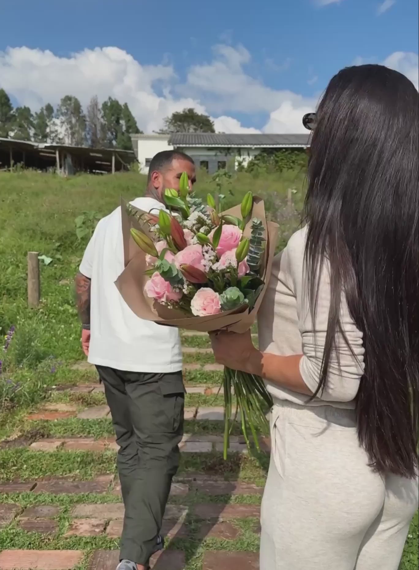 Short video showcase of a model with a bouquet in outdoors wearing the Flirty Jumpsuit in Cozy oat color