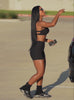 A short video of a model walking away from her car wearing our Tiny Waist Shorts in Onyx color and a matching sports bra