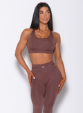 Front  profile view of a model in our barbell sports bra in chocolate color and a matching leggings