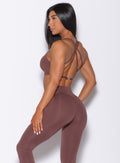 Left side profile view of a model in our barbell sports bra in chocolate color and a matching leggings