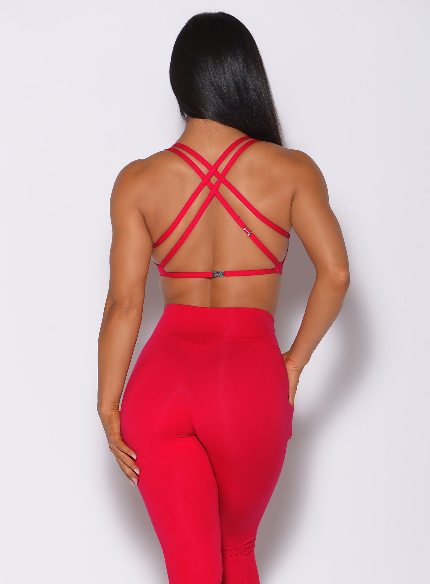 Back profile view of a model in our red barbell sports bra and a matching leggings 