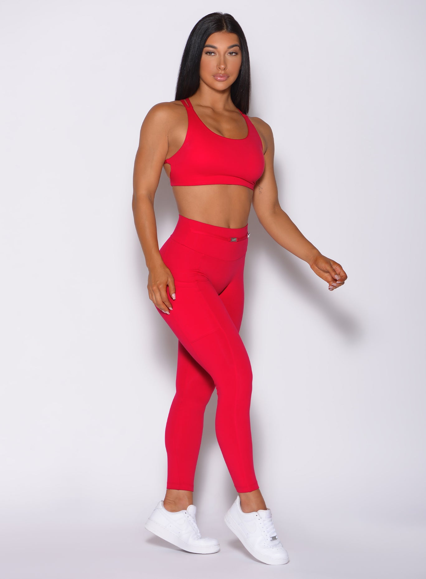 Right side profile view of a model facing forward wearing our red barbell sports bra and a matching leggings