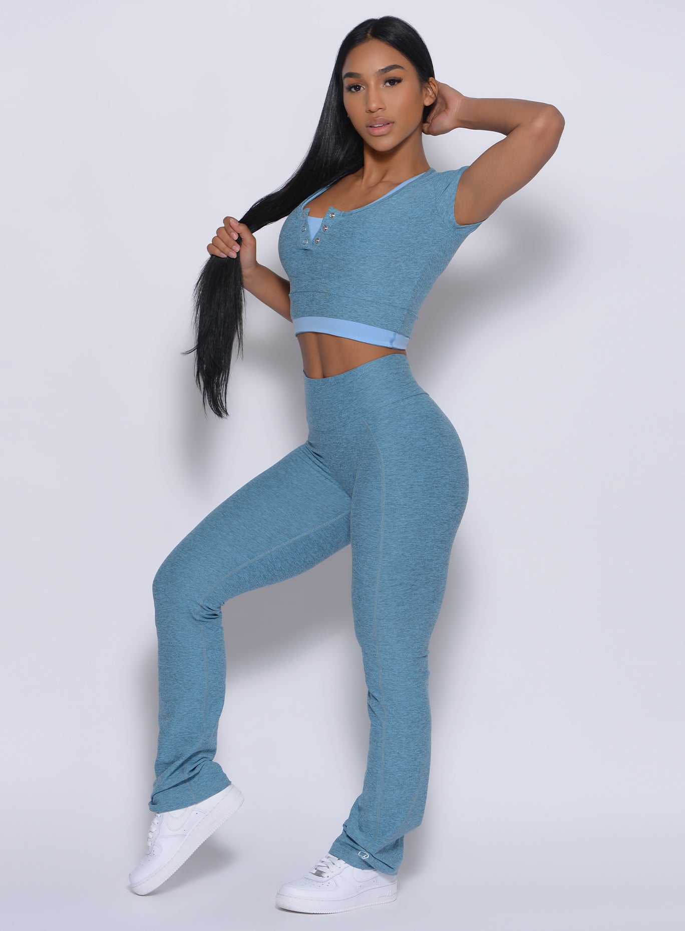 Left side profile view of a model holding her hair wearing our straight up leggings in baby blue color and a matching bodysuit