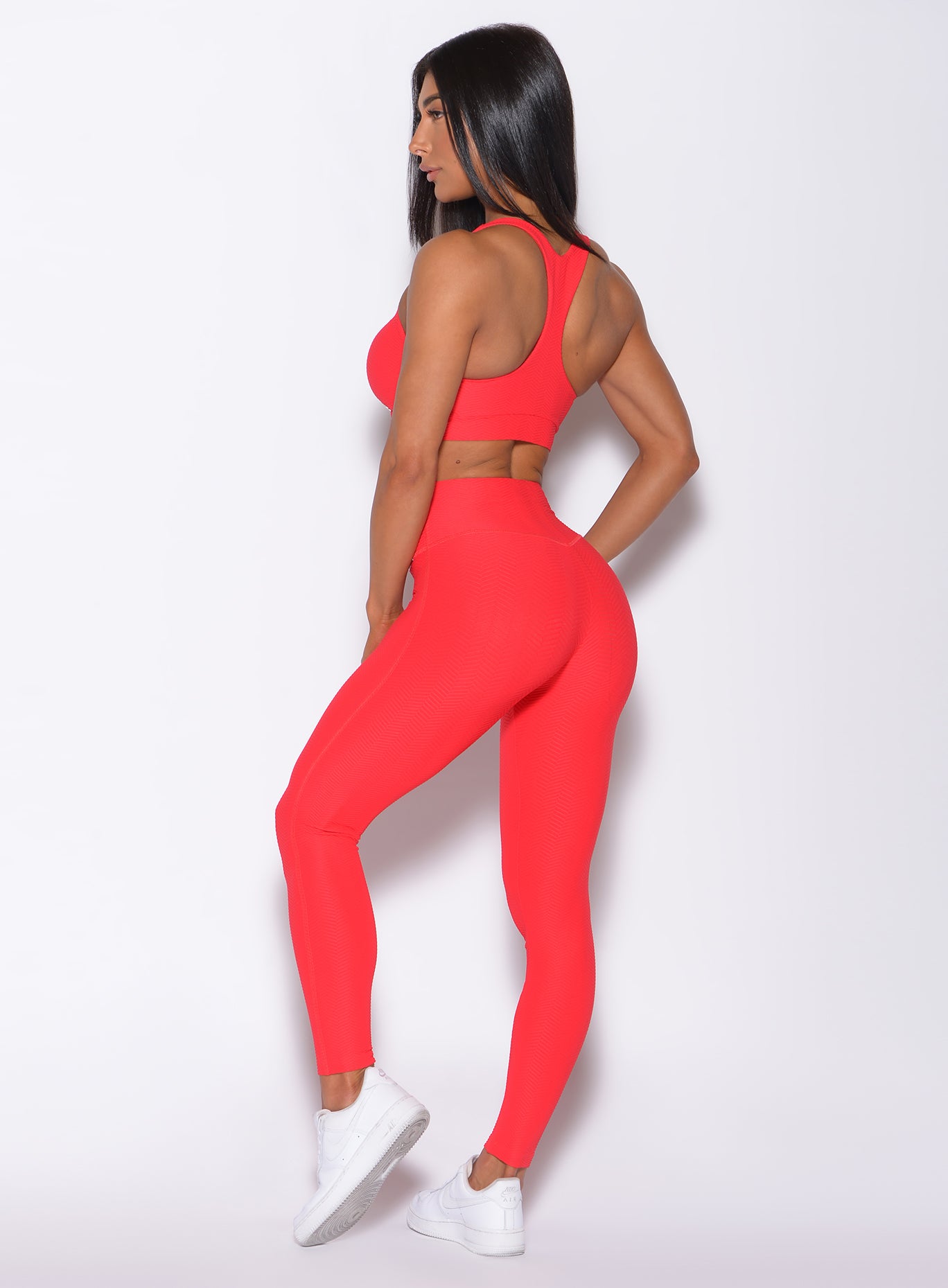 Back profile view of a model in our Chevron Leggings in flame red color and matching bra