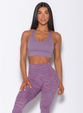 Front  profile view of a model in our rival sports bra in solid orchid color and a matching sexy back leggings in tiger print