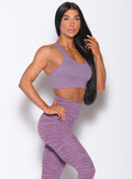 Right side profile view of a model angled to her right wearing our rival sports bra in solid orchid color and a matching sexy back leggings in tiger print 