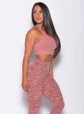 Right side profile view of a model in our rival sports bra in solid blush color and a matching tiger print leggings