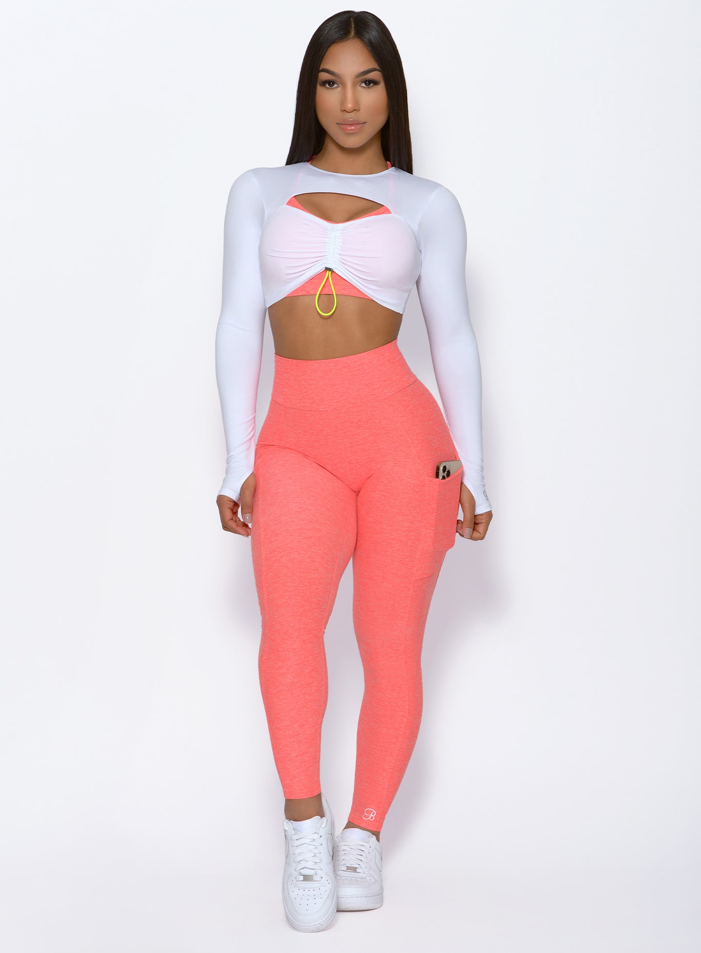 front profile view of a model wearing our Curve leggings in Coral and our Pullover in White