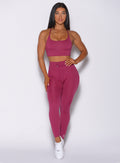 Front profile view of a model wearing our empower leggings in berry good color and a matching sports bra