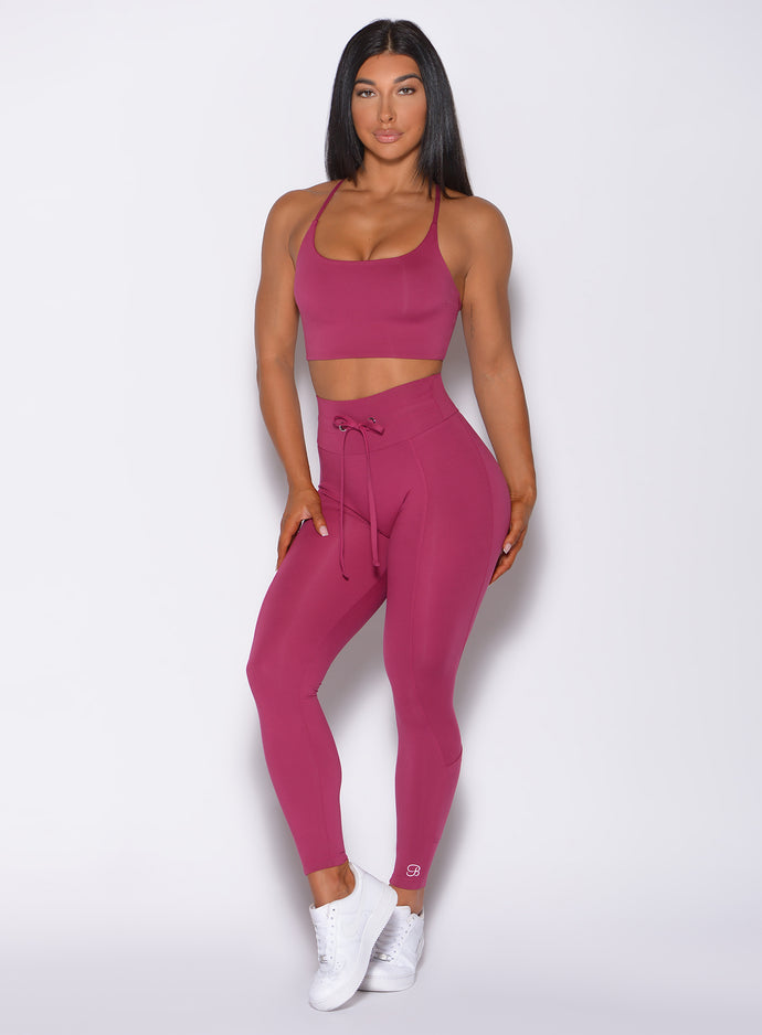 Front profile view of a model wearing our empower leggings in berry good color and a matching bra