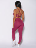 Back profile view of a model in our empower leggings in berry good color and a matching bra