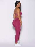 Right side profile view of a model in our empower leggings in berry good color and a matching bra