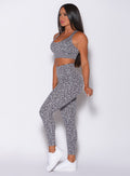 Left side profile view of a model wearing our fit cheetah leggings in lightning gray color and a matching bra