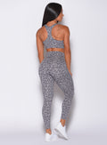 Back profile view of a model wearing our fit cheetah leggings in lightning gray color and a matching bra