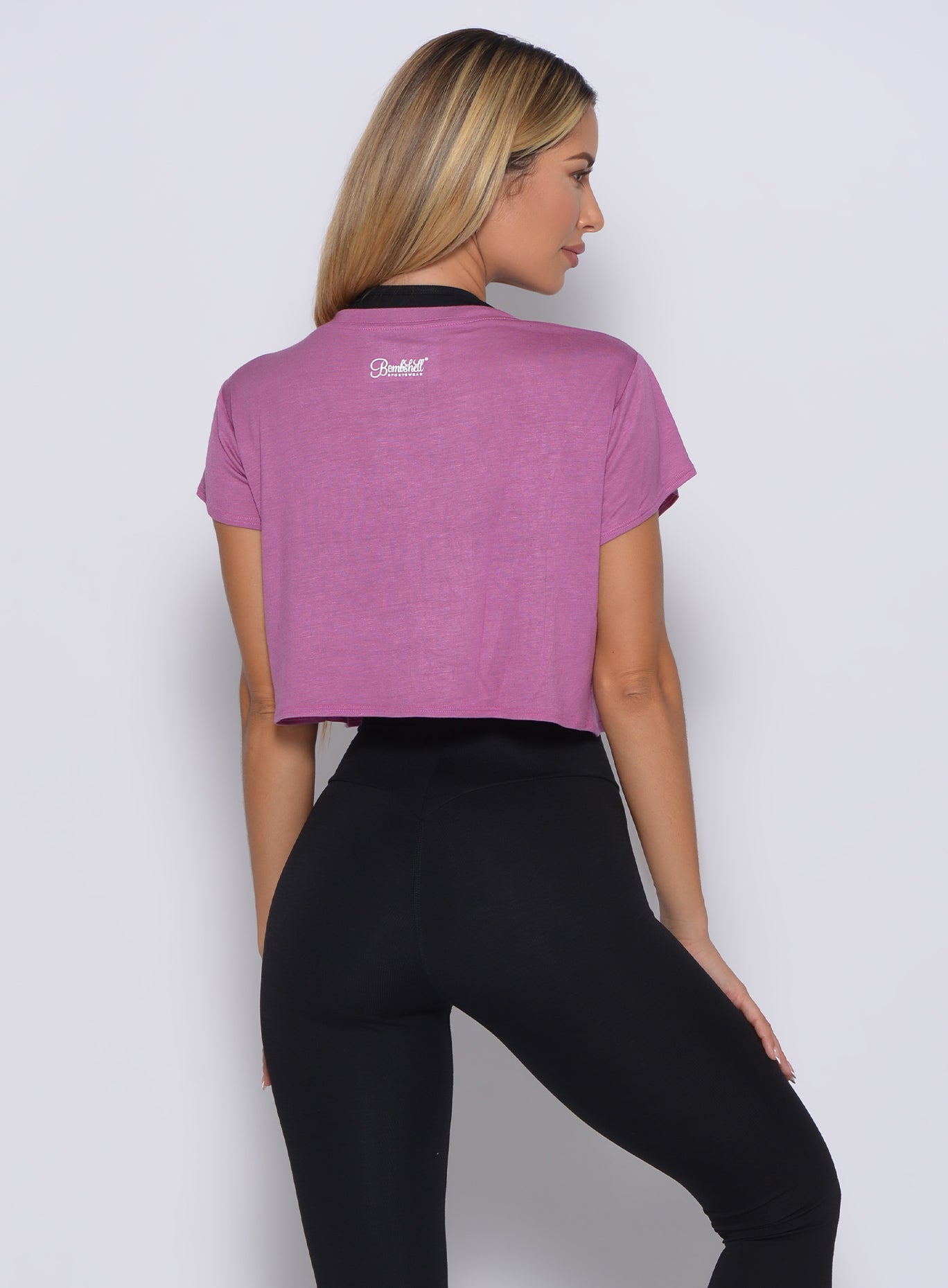 Back profile view of a model in our freedom tee in strawberry pink color and a black leggings