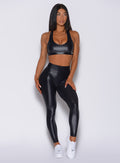 Picture of a model facing forward wearing our black power gloss bra and a black gloss leggings