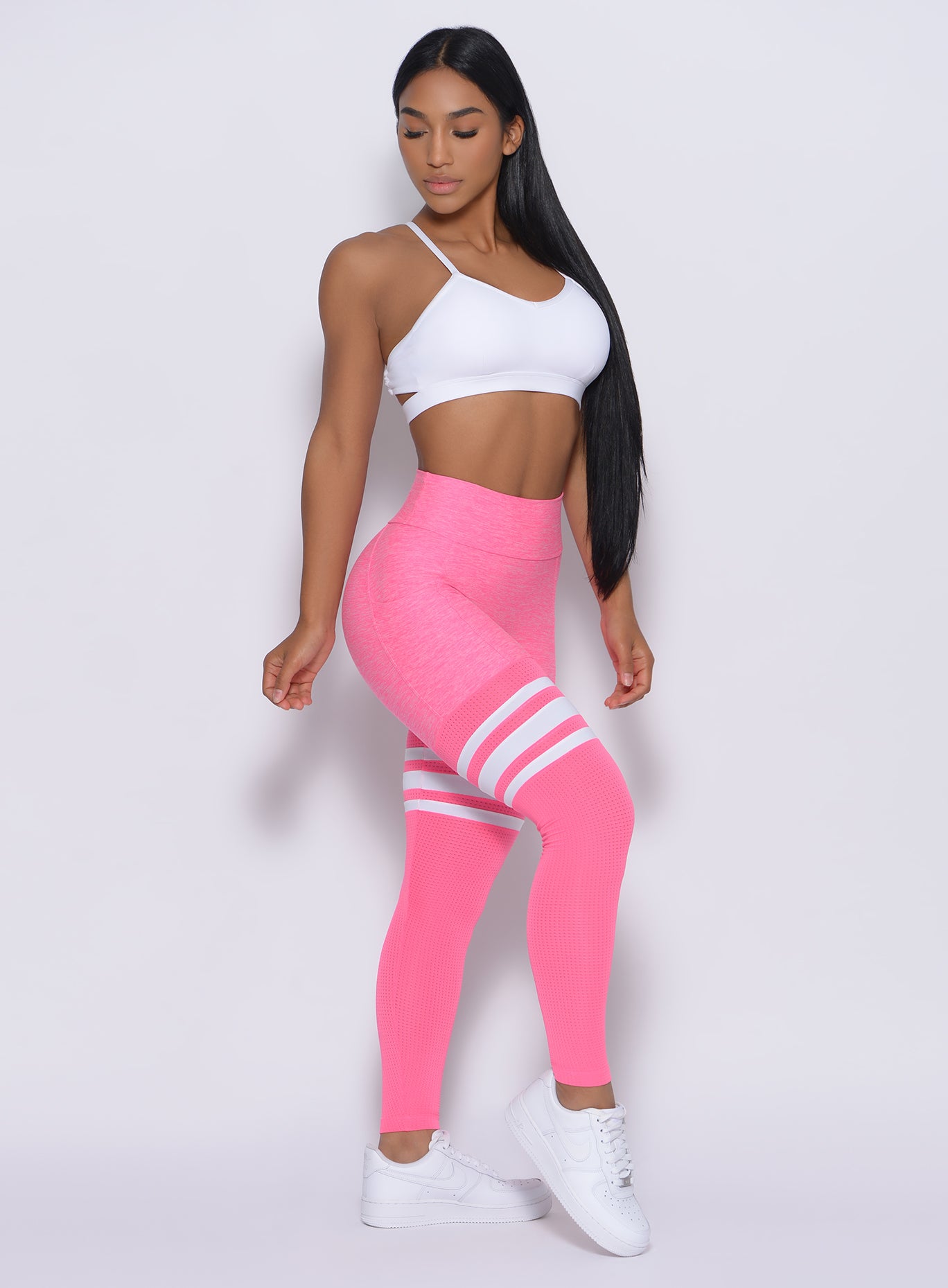 Right side profile view of a model angled right wearing our  Scrunch Thigh High in Hollywood Pink color and a White Sports bra