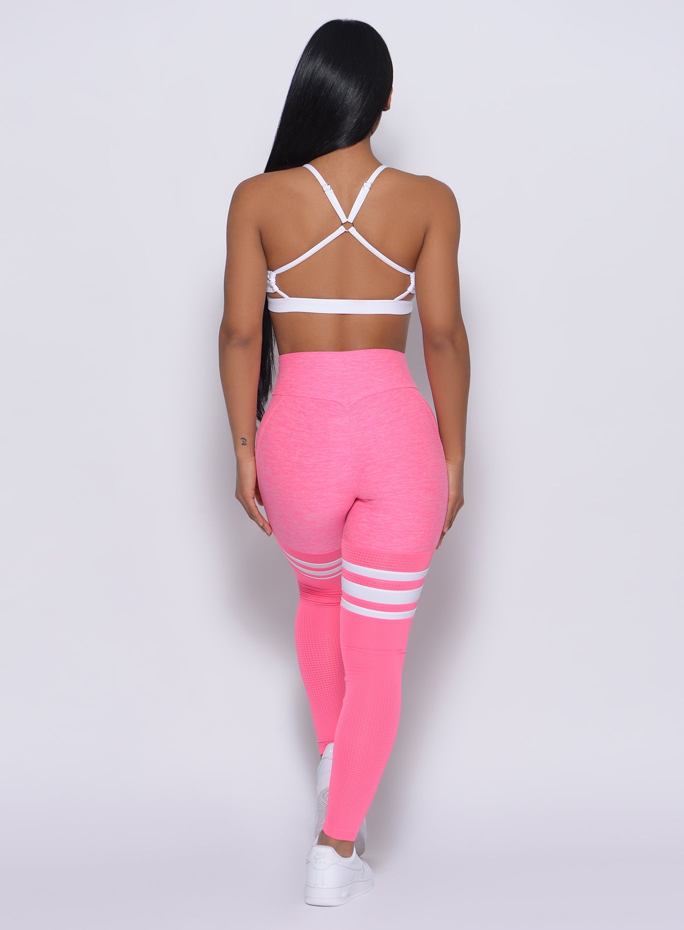 back profile of model wearing the Scrunch Thigh High in Hollywood Pink color and a White Sports bra