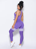 back profile of model facing to her left wearing our perform thigh highs in royal purple color with three white stripes on thighs and a matching bra