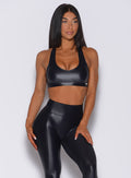 front profile view of a model posing in our black power gloss bra and a matching gloss leggings   