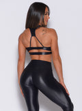 profile view of a model wearing our black power gloss bra and a matching gloss leggings