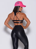 Back profile view of a model in our black power gloss bra and a matching black gloss leggings