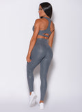 Back profile view of a model angled right wearing  our shine leggings in gray python color and a matching bra