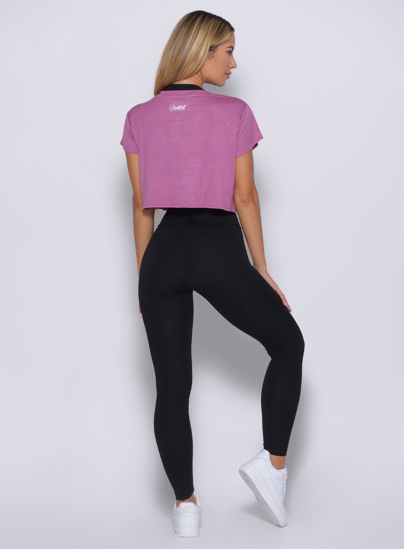 Back profile view of a model in our freedom tee in strawberry pink color along with a black high waisted leggings
