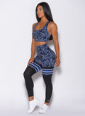 Left side profile view of a model facing forward wearing our scrunch thigh high in blue leopard print and a matching sports bra