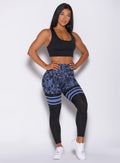 Front profile view of a model in our scrunch thigh high in blue leopard print and a black sports bra 