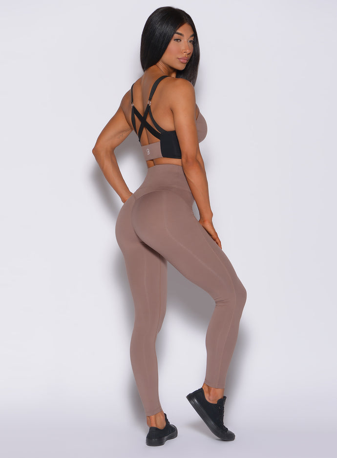 Right side profile view of a model in our snatched waist leggings in cocoa color and a matching bra