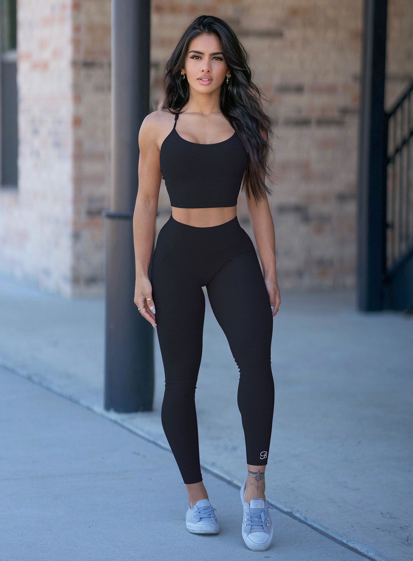 Front profile view of a model wearing our black uplift leggings and a matching bra